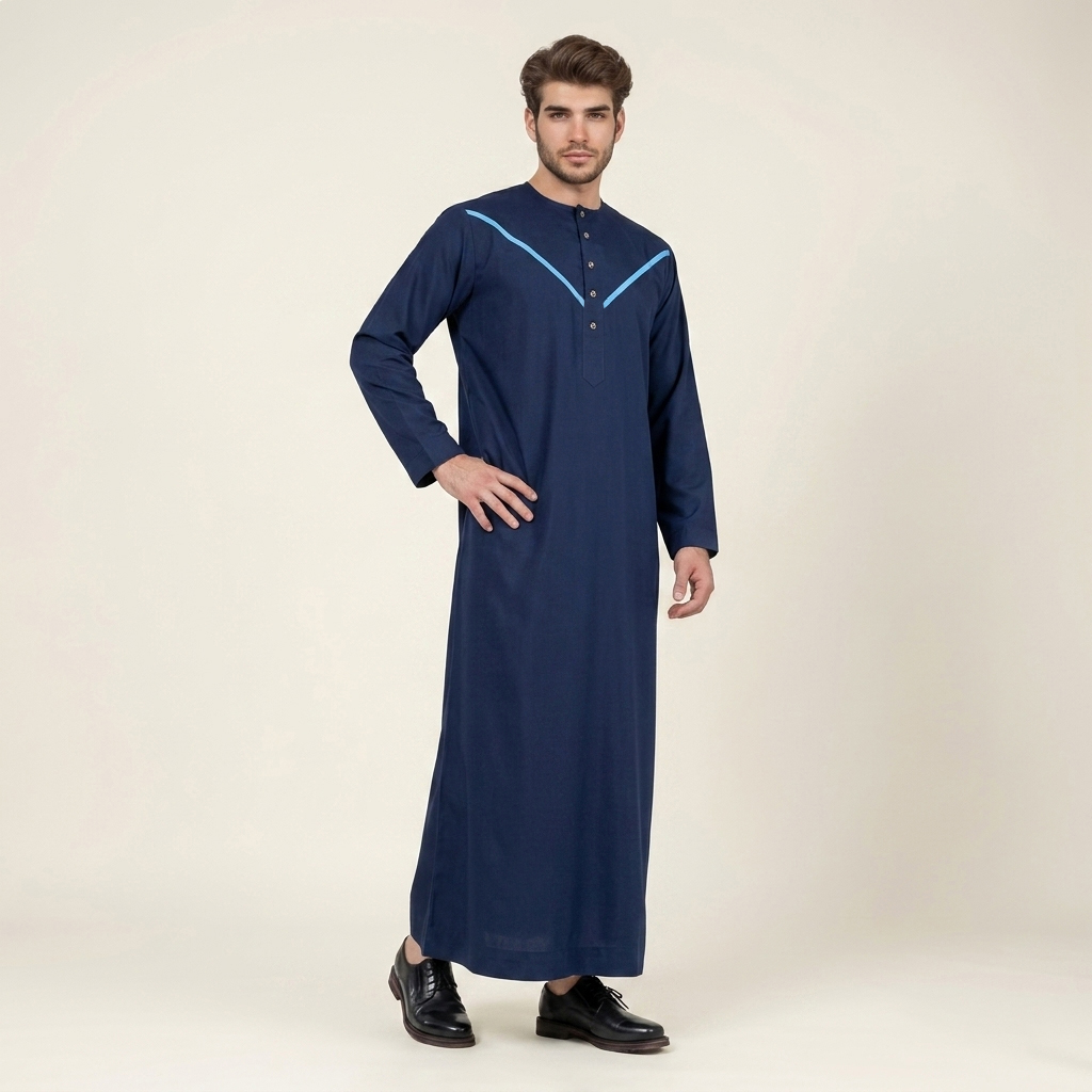 Elevate your style with our Omani Style Navy Blue Mens Thobe, designed to blend traditional elements with modern detailing. Featuring a deep navy base with striking sky blue accents, this thobe offers a refined and contemporary look suitable for formal gatherings, prayers, and everyday wear. Its structured design and premium fabric ensure both comfort and sophistication. Design & Cut This thobe is tailored with a straight-cut silhouette that provides a clean and structured appearance. The signature V-stitch yoke across the chest adds a bold geometric detail, enhancing the overall design with a modern touch. Fabric Crafted from premium wash & wear fabric, the material is wrinkle-resistant and easy to maintain. It retains a smooth and crisp drape throughout the day while ensuring durability and long-lasting wear. Collar / Neckline The thobe features a modern collarless round neckline, offering a comfortable and streamlined fit. This minimalist design enhances both style and ease of wear. Closure & Pockets A neat front placket with vertically aligned buttons adds a refined and professional detail. The design maintains a clean aesthetic while ensuring functionality and convenience. Sleeves The full-length sleeves are designed for a polished finish, complementing the structured silhouette while allowing comfortable movement. Overall Design The Omani Style Navy Blue Mens Thobe stands out with its bold V-stitch detailing and rich color contrast. With its breathable fabric, modern tailoring, and traditional inspiration, it is a versatile choice for formal occasions and everyday elegance.